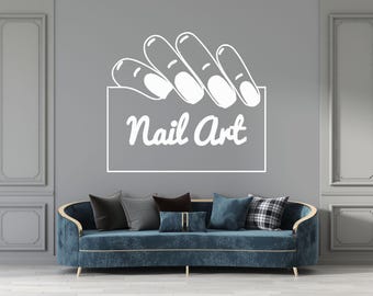 May include: A white silhouette of a hand with manicured nails holding a sign that says "Nail Art". The sign is on a gray wall behind a blue sofa.