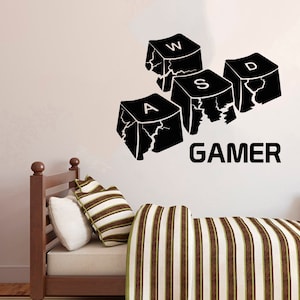 May include: Black and white wall decal featuring four broken keyboard keys spelling out "WASD" and the word "GAMER".