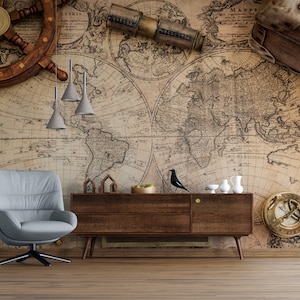 Könnte beinhalten: Eine Vintage-Weltkarte Tapete mit einem braunen Holzsteuerrad, einem Teleskop und einem Kompass. Ein grauer Sessel steht vor einer Kommode aus Holz mit einer Schale Obst darauf.