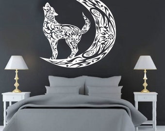 May include: A white wolf howling at a crescent moon, both with intricate tribal patterns, against a dark gray wall. The artwork is a wall decal, suitable for bedroom decor. The image includes a bed, nightstands, and lamps.