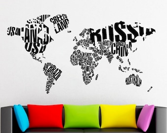 May include: A black and white world map made of text, with the names of countries and continents. The map is on a white wall behind a gray couch with colorful pillows.