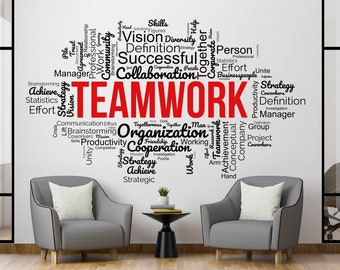May include: A white wall with a black and red word cloud that says "TEAMWORK" in red letters. The word cloud is surrounded by words related to teamwork, such as "collaboration", "organization", "strategy", and "achievement". There are two gray armchairs with white pillows in front of the wall.