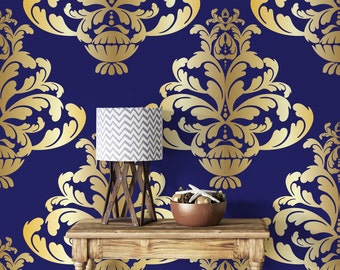 May include: A wooden table with a gold and blue damask patterned wallpaper. A lamp with a chevron patterned lampshade sits on the table. A bowl with decorative items sits on the table.