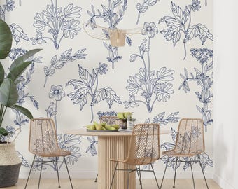May include: A dining room with a white background featuring a blue floral wallpaper pattern. A round wooden table with four wicker chairs sits in the center of the room. The table is decorated with a bowl of fruit and a glass of water.