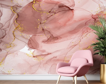 May include: A pink armchair with wooden legs sits in front of a wall with a pink and gold abstract design. The wall features a swirling pattern of pink and white with gold accents.