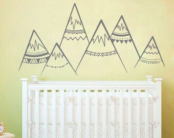May include: Gray mountain range wall decal with geometric patterns. The decal is applied to a light yellow wall above a white crib.