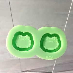 Può includere: Uno stampo in silicone verde chiaro con due disegni di facce di rana. Lo stampo ha una superficie liscia ed è progettato per l'artigianato. Il marchio "GoZgi" è stampato sullo stampo.