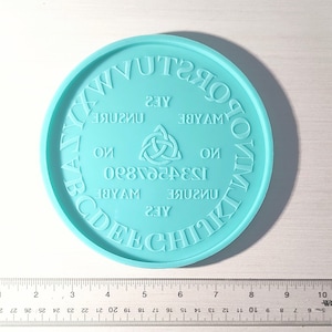 May include: A light blue circular silicone mould with the words "YES", "MAYBE", "NO", "UNSURE", "1234567890", and "YES" written around the edge. The mould also features a Celtic knot design in the centre.