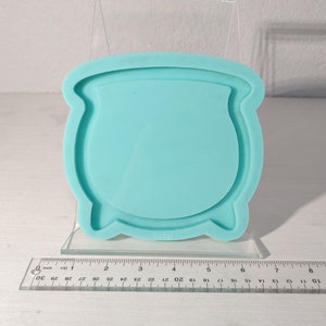 May include: A light blue silicone mould shaped like a cauldron. The mould is approximately 10 cm wide and 7.5 cm tall.