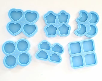May include: Set of seven blue silicone moulds for making resin crafts. The moulds are shaped like hearts, stars, moons, clouds, circles, and squares.