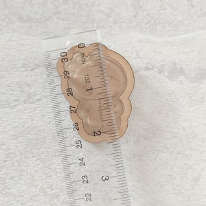 May include: A clear plastic bear-shaped mold for resin casting, measuring approximately 2 inches in diameter. The mold is placed on a ruler for size reference.