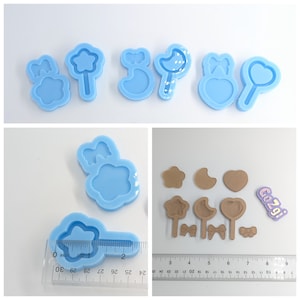 May include: A set of six blue silicone molds for making resin crafts. The molds are shaped like a star, a crescent moon, a heart, a bow, and a flower. The molds are approximately 2 inches in length.
