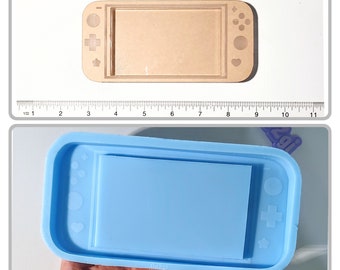May include: A blue silicone mold shaped like a Nintendo Switch console. The mold has a raised design of the console's buttons and screen.