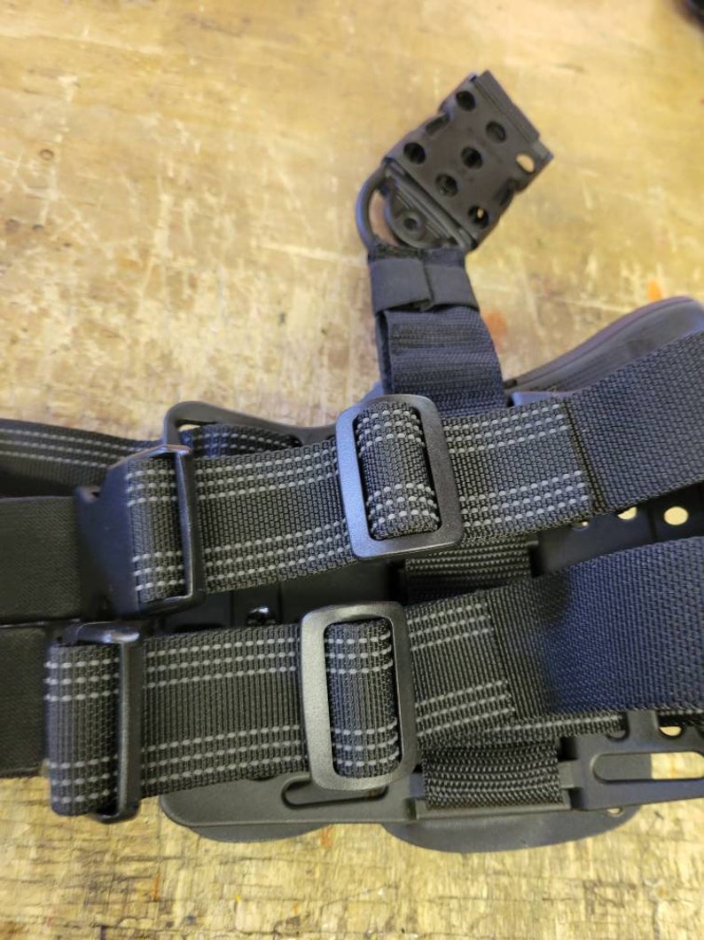 May include: Black tactical belt with two adjustable straps and a black plastic holster with a loop on top.