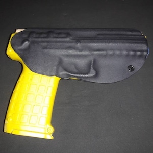 May include: A yellow handgun with a black holster. The handgun has a textured grip and is partially covered by the holster. The holster is black and appears to be made of a durable material.