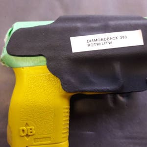May include: A yellow and green handgun with a black holster. The holster has a label that reads "DIAMONDBACK 380 ROTW/LITW".