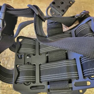 May include: Black tactical holster with adjustable straps and a belt loop. The holster is made of durable nylon and has a secure fit.
