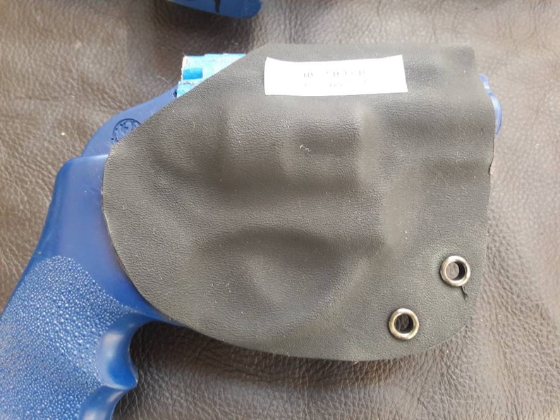 May include: A blue handgun with a black leather holster. The holster has two metal eyelets and the text "38 SPECIAL" printed on it.