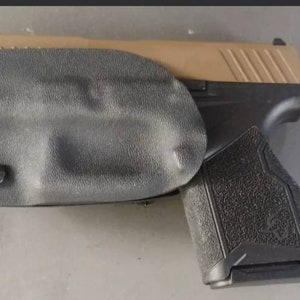 May include: A black and tan handgun with a black holster. The holster has two screws on the side.