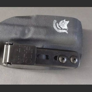 May include: Black leather holster with a metal clip and two screws. The holster has a white logo on the top.