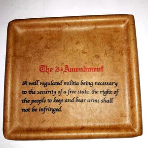 Puede incluir: Una bandeja de cuero marrón con el texto "The 2nd Amendment" y el texto de la Segunda Enmienda de la Constitución de los Estados Unidos.