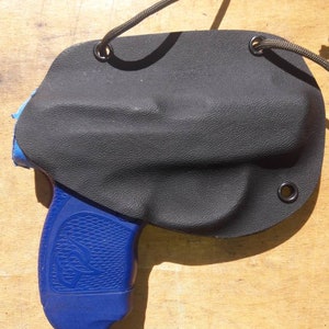 Peut inclure: Un &eacute;tui en cuir noir avec un pistolet bleu et noir &agrave; l'int&eacute;rieur. L'&eacute;tui est dot&eacute; d'une fermeture &agrave; cordon et est con&ccedil;u pour &ecirc;tre port&eacute; sur la hanche.