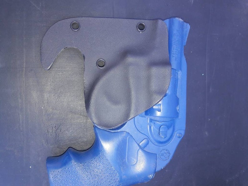 May include: A blue handgun with a black leather holster. The holster has a hook on the top and multiple holes for attaching to a belt.