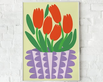 May include: A framed art print featuring a stylized illustration of red tulips in a purple and white scalloped vase. The background is a pale yellow, and the print is framed in white. The artwork is displayed against a white brick wall.