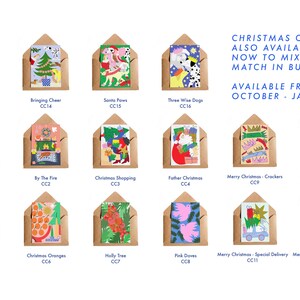 May include: A collection of Christmas cards in kraft paper envelopes. Each card features colorful illustrations with titles like "At The Window," "Bringing Cheer," and "Santa Paws." Text on the right says "Christmas Cards" and "Available from October - January."
