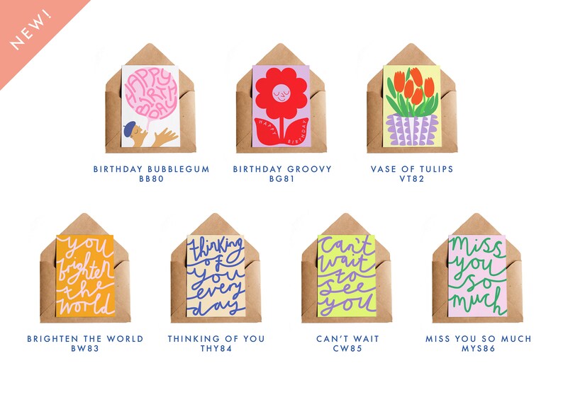 May include: A collection of greeting cards in kraft paper envelopes. The cards feature colorful illustrations and handwritten text, including phrases like "Happy Birthday," "Thinking of You," and "Miss You So Much." The word "NEW!" is in the upper left corner.