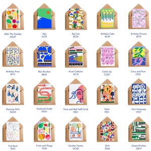 May include: A collection of greeting cards in brown envelopes. Each card features a unique, colorful illustration. Designs include fruits, flowers, abstract art, and birthday themes. The cards are labeled with titles and codes like "After The Garden AG47."