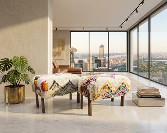 May include: Two rectangular ottomans featuring thick, cream-colored shaggy wool upholstery with vibrant, multi-colored geometric zigzag patterns in pink, yellow, blue, and black, supported by four dark brown wooden legs each.