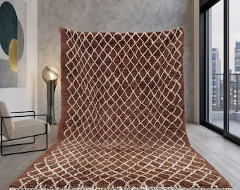 May include: A large, rectangular brown rug with a white diamond pattern. The rug has a shaggy texture and a fringe along the bottom edge. The rug is displayed in a modern living room setting.