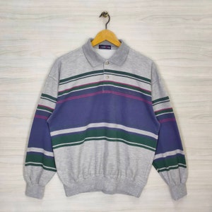 May include: A gray, long-sleeved polo shirt with blue, green, and pink stripes. The shirt has a button-up collar and a small logo on the chest that says "Golf Club".
