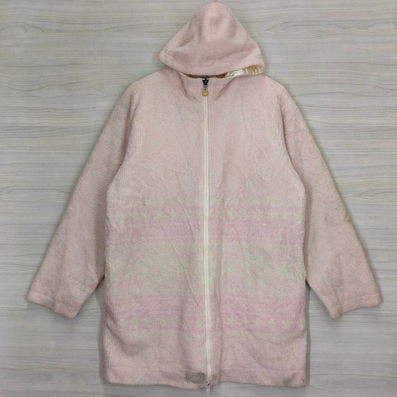 May include: A pink hooded jacket with a white and pink patterned design. The jacket has a zipper closure and long sleeves.
