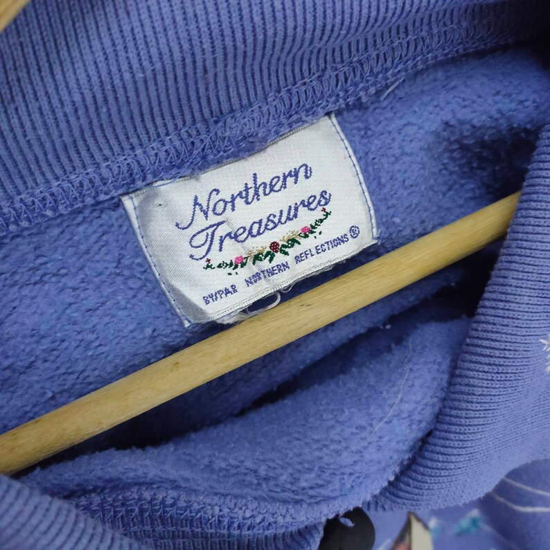 May include: A purple sweatshirt with a white tag that reads "Northern Treasures" and "By PAR Northern Reflections".
