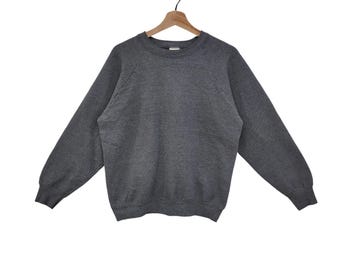May include: A heather gray sweatshirt with long sleeves, displayed on a wooden hanger. The crew neck sweatshirt is made of a soft material. The garment is a casual style.