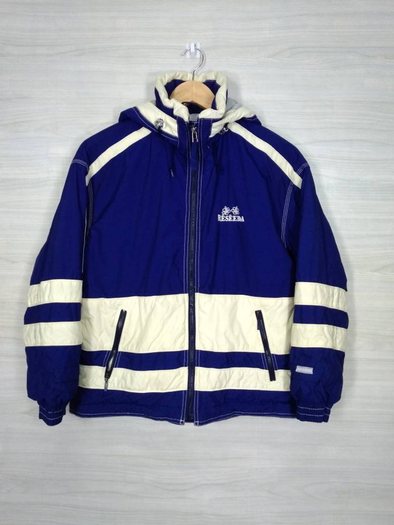 May include: A blue and white striped hooded jacket with a zip closure. The jacket has a logo that says "RESEEDA" on the front.