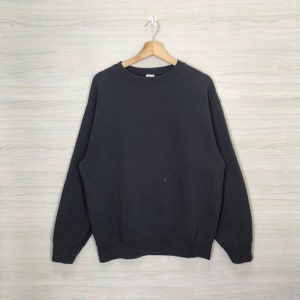 Könnte beinhalten: Ein schwarzer Rundhals-Pullover mit langen Ärmeln.