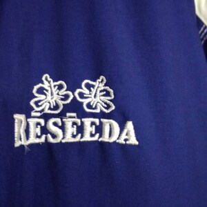 May include: A blue jacket with white embroidered flowers and the word "RESEEDA" on the front.