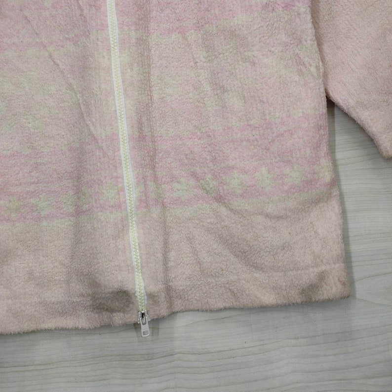 May include: A pink fleece jacket with a white zipper and a white and pink patterned design.