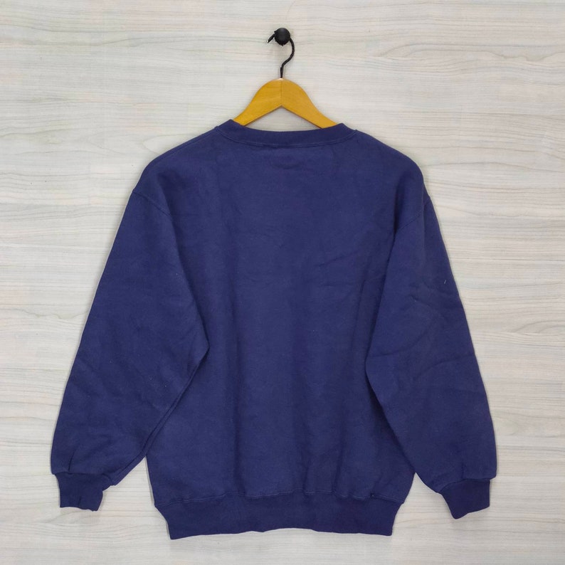 Pode incluir: Uma camisa de moletom azul escura de manga comprida e gola redonda.