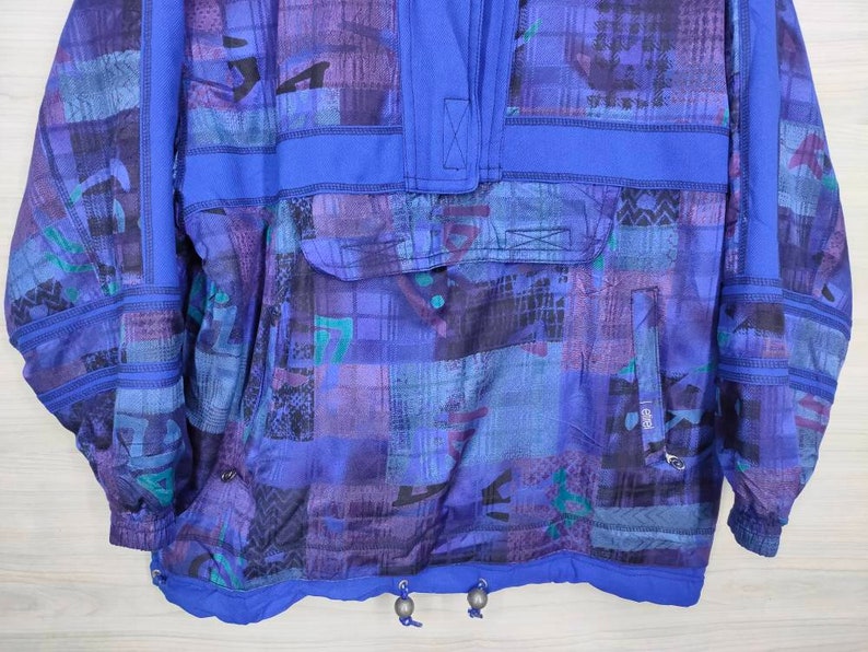 Puede incluir: Una chaqueta de color azul y morado con estampado, con cremallera y capucha con cord&oacute;n. La chaqueta tiene un bolsillo grande en la parte delantera y un bolsillo m&aacute;s peque&ntilde;o en la manga izquierda.
