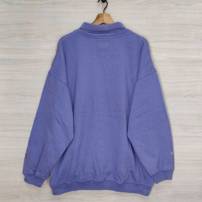 May include: A purple sweatshirt with a zippered collar and long sleeves.