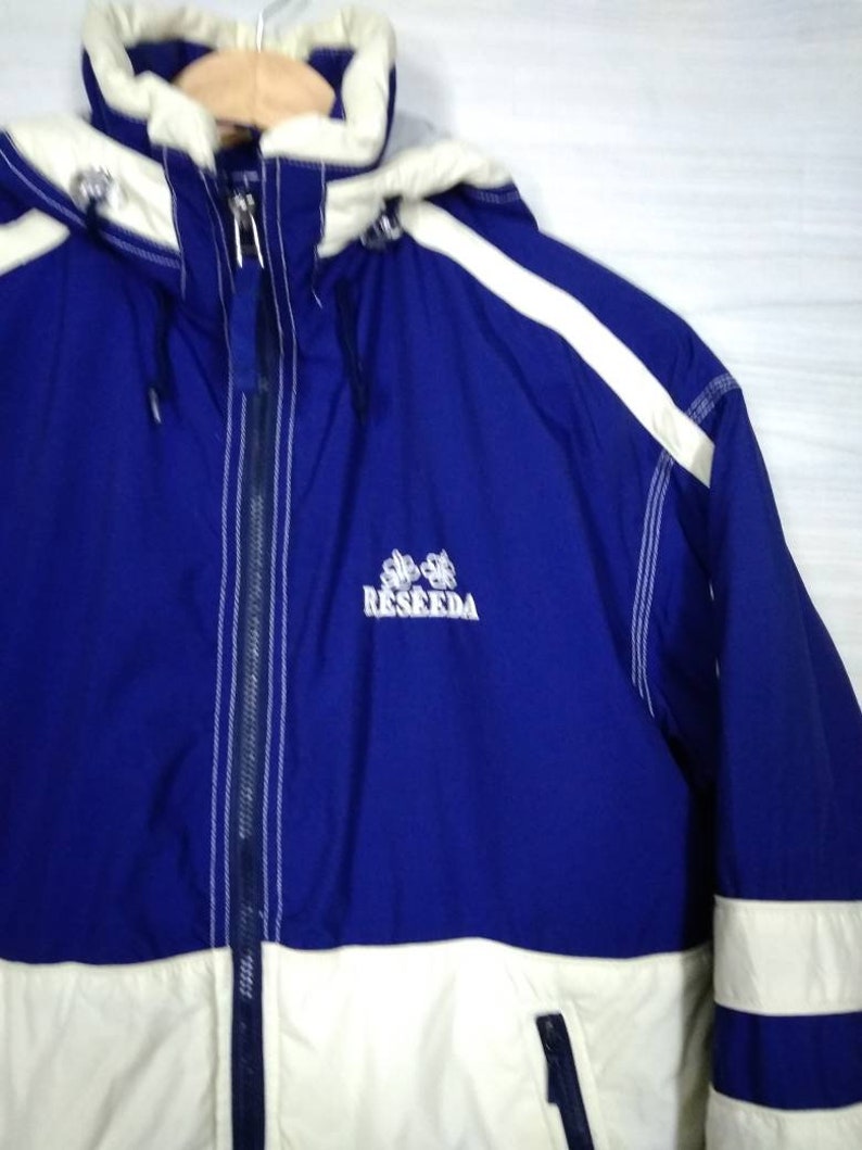May include: A blue and white hooded jacket with a white stripe down the sleeve and the word "RESEEDA" embroidered on the front.