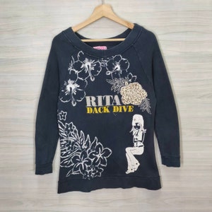 May include: Black long-sleeved sweatshirt with a white graphic print of flowers, a woman, and the text "RITA DACK DIVE".