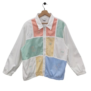 May include: A white jacket with a zip fastening and a patchwork design. The patches are in various colours, including pink, blue, yellow, and green. Each patch has a different embroidered design, including fish, stars, and flowers.