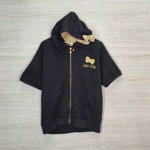 May include: Black hooded zip-up sweatshirt with short sleeves. Features a gold zipper, a gold bow and "Hello Kitty" embroidered on the front. The hood lining has a tan and brown animal print.