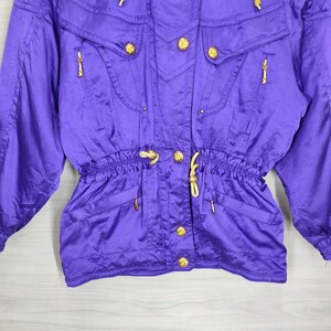 May include: Purple ski jacket with gold buttons and a drawstring waist.