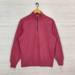 May include: A burgundy quarter-zip sweatshirt with a small logo on the chest.